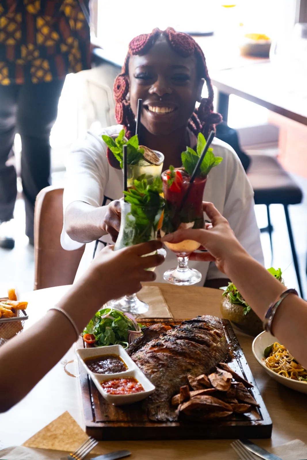 Friends toasting over grilled fish and sharing dishes